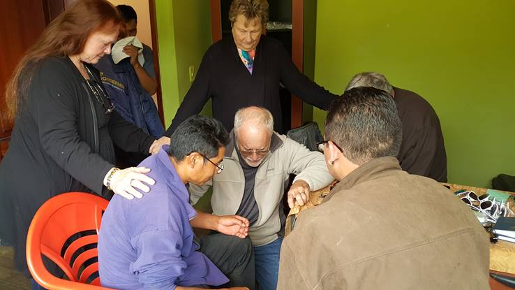 Abide in Christ team praying with new believer in Christ.